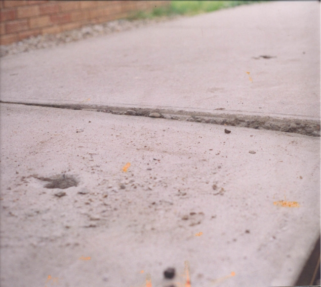 A sunken concrete sidewalk in desperate need of repair