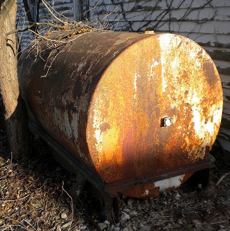 This above-ground oil storage tank has severely rusted and can pose environmental hazards as well as threaten the adjacent structure.